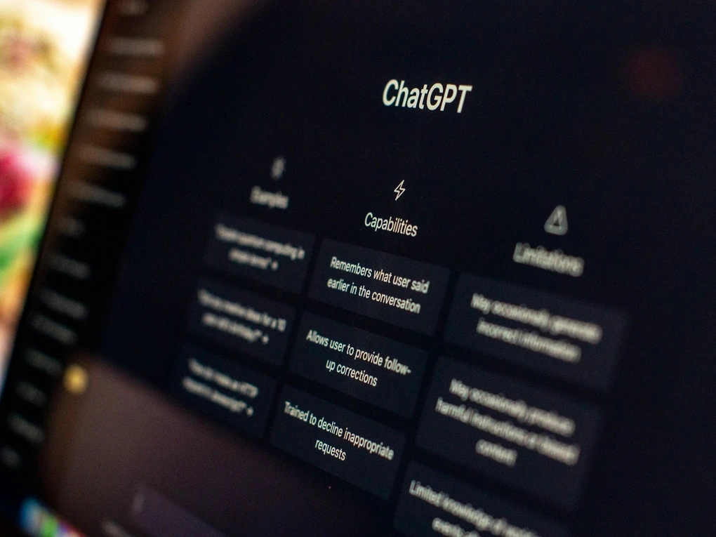 A laptop screen showing the ChatGPT home page with its Examples, Capabilities, and Limitations columns.